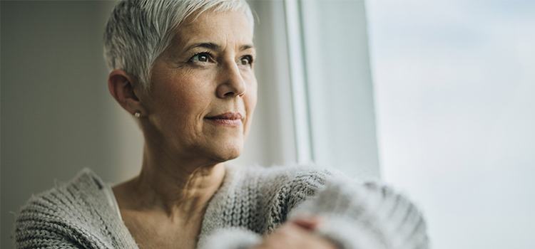 older woman looks out of window 