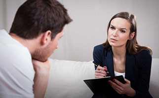 woman takes notes talking with male patient