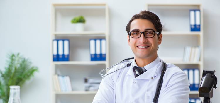 occupational therapist with glasses smiles and lab coat smiles at camera