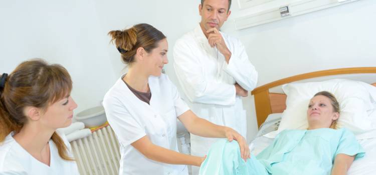 occupational therapy student tends to patient as her supervisor looks on