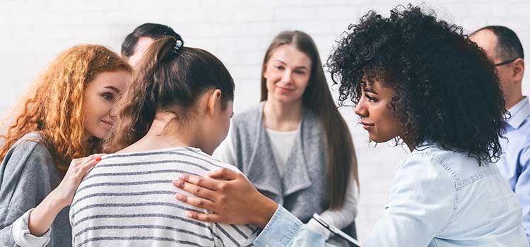 grief counseling group console distraught member as counselor looks on