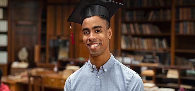 graduate student standing in university library wearing mortarboard