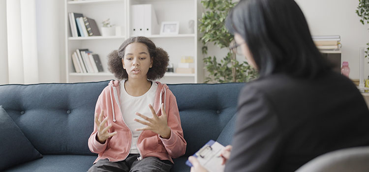 female youth counselor listens to teenager discuss issues in provate session