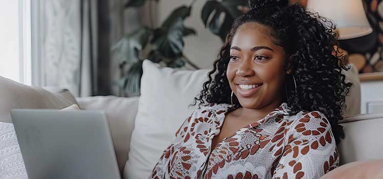 woman on laptop sitting on sofa applying for jobs