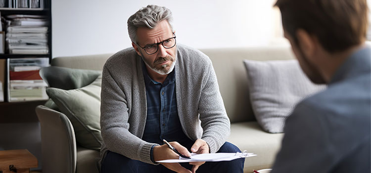 serious counselor discusses substance abuse issues in california office with patient