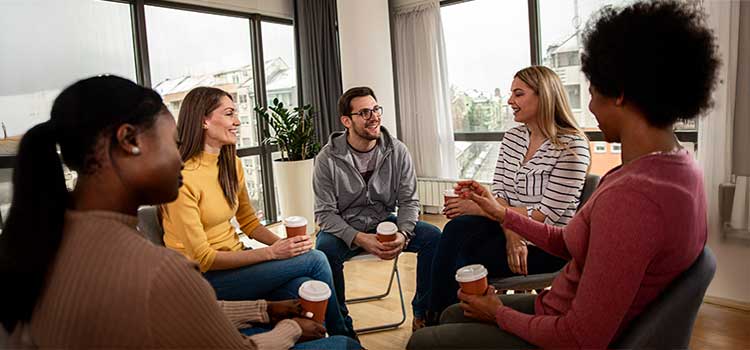substance abuse counselor sits with patient group holding lattes