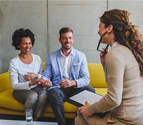 couple in marriage counseling share a lighter moment with their marriage and family therapist in california