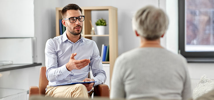 clinical psychologist conferring with patient in stark office