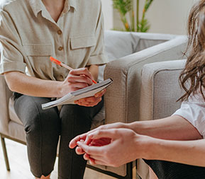 a counselor takes notes while speaking with a client